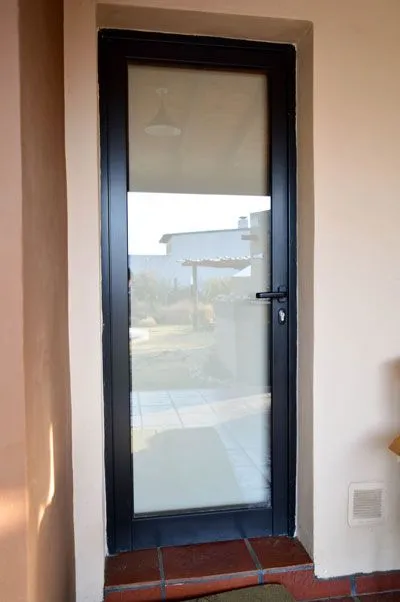 Puerta de aluminio negro con vidrio entero y salida a la galería