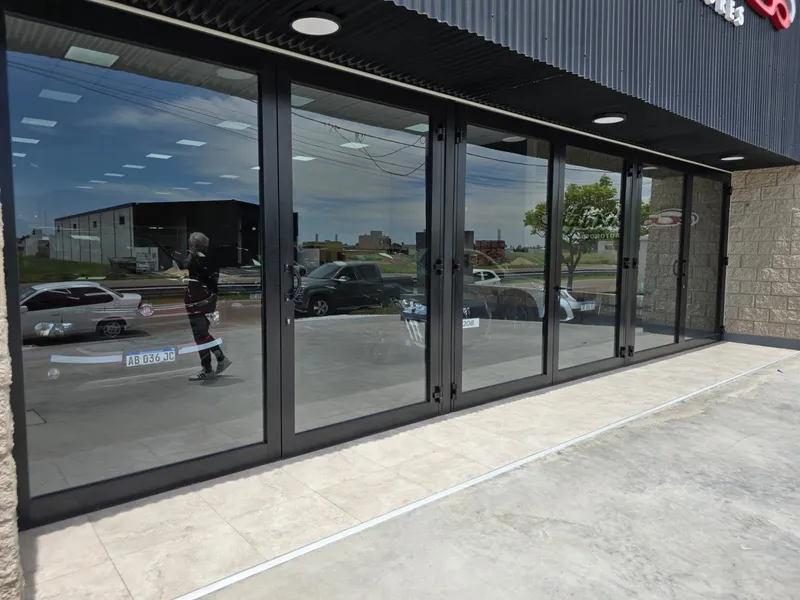 Paños fijos y puertas de PVC negro en el lateral del salón de ventas