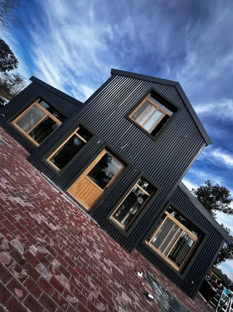 Fachada de chapa negra en Lincoln con ventanas y puerta de PVC roble dorado