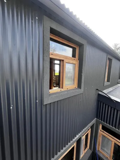 Ventanas de PVC roble dorado sobre el lateral revestido en chapa sinusoidal negra