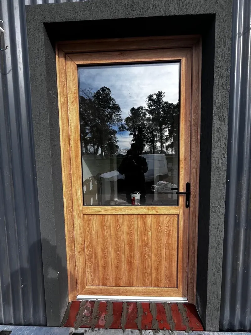Puerta de PVC roble dorado con paño de vidrio y zócalo ciego