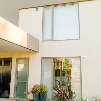 Ventana alta de aluminio en planta alta y puerta con postigón de celosía