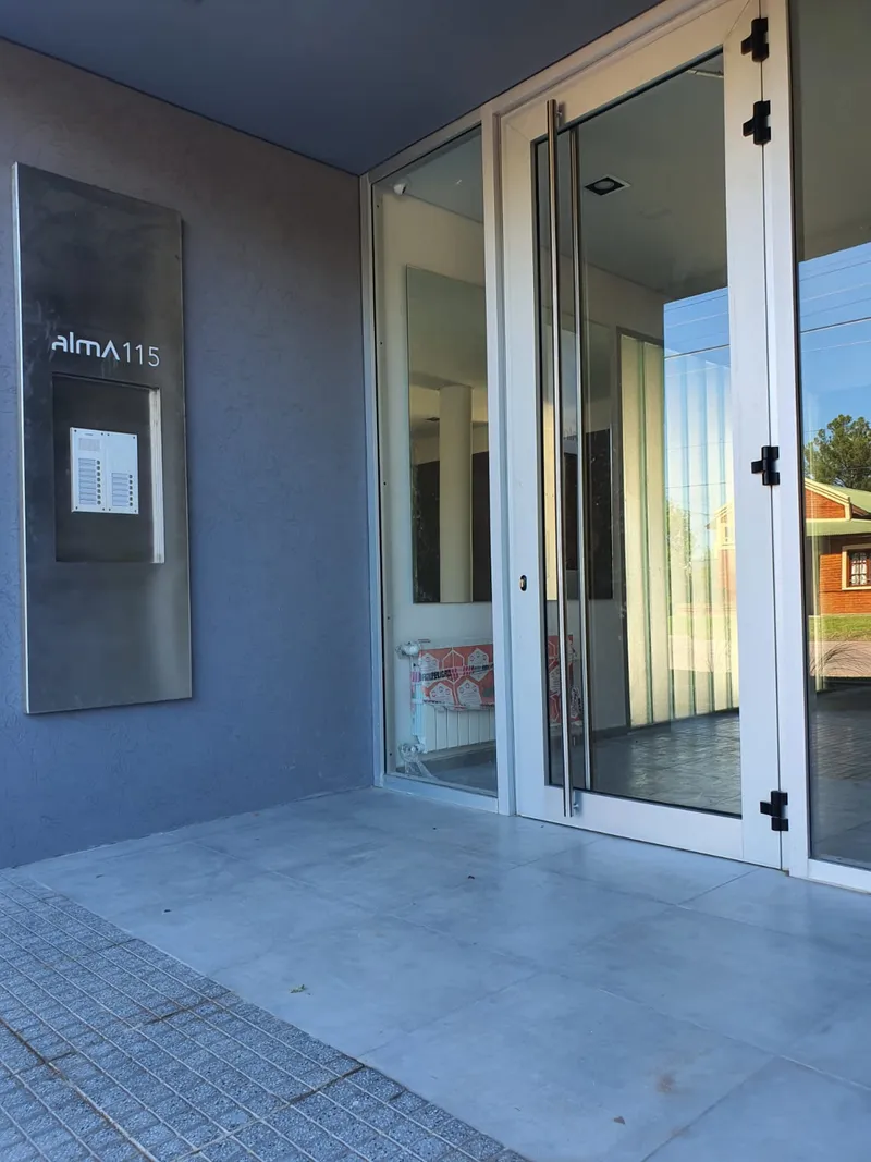 Acceso al complejo Alma 115 con puerta y paños fijos de aluminio
