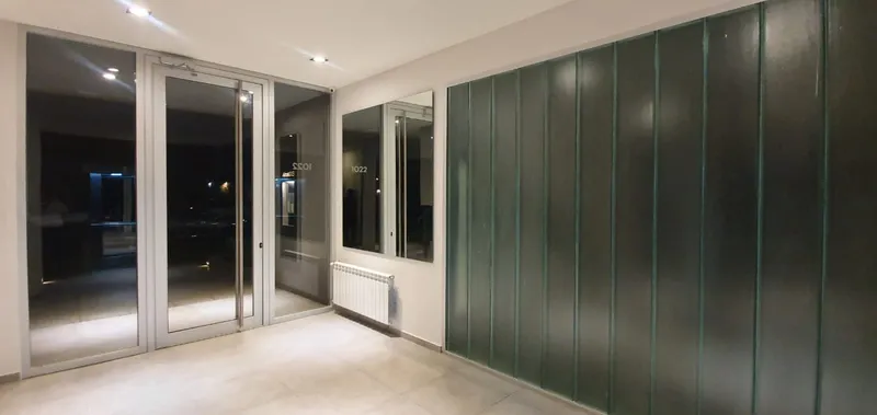 Paños fijos y puerta de aluminio anodizado en el estar de un departamento