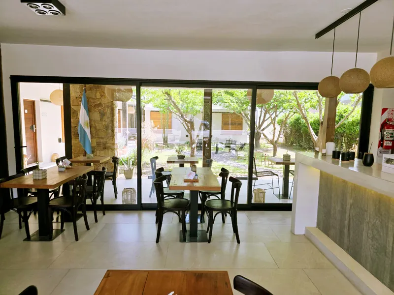 Comedor del hotel con ventanal corredizo de aluminio negro abierto al patio