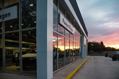 Lateral del concesionario con piel de vidrio y perfilería de aluminio al atardecer