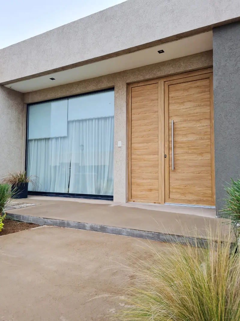 Puerta de entrada y ventanal corredizo de PVC Turner bajo el alero de la casa