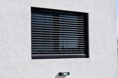 Celosía de aluminio bronce anodizado sobre la ventana del dormitorio