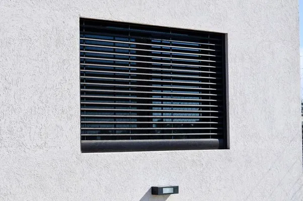 Celosía de aluminio bronce anodizado sobre la ventana del dormitorio