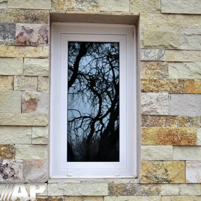 Ventana de abrir de PVC blanco sobre el muro de piedra