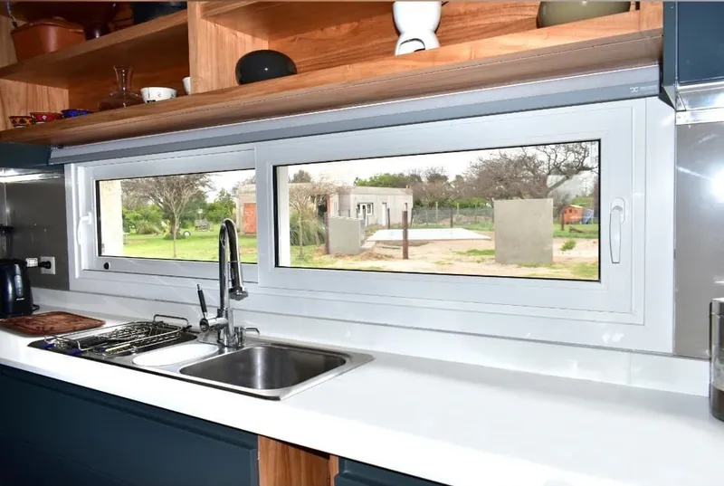 Ventana apaisada oscilobatiente de PVC blanco sobre la mesada de la cocina