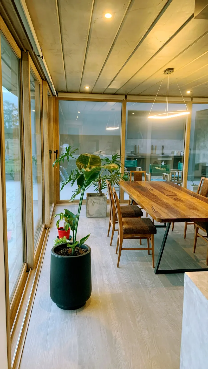 Galería vidriada con paños corredizos de PVC Turner y techo de madera