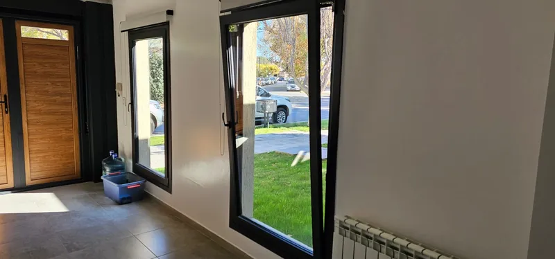 Interior con puerta de PVC Turner y ventanales negros hacia el jardín