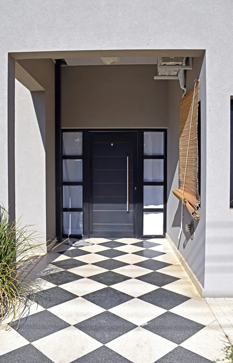 Puerta de entrada de aluminio negro con paños fijos laterales