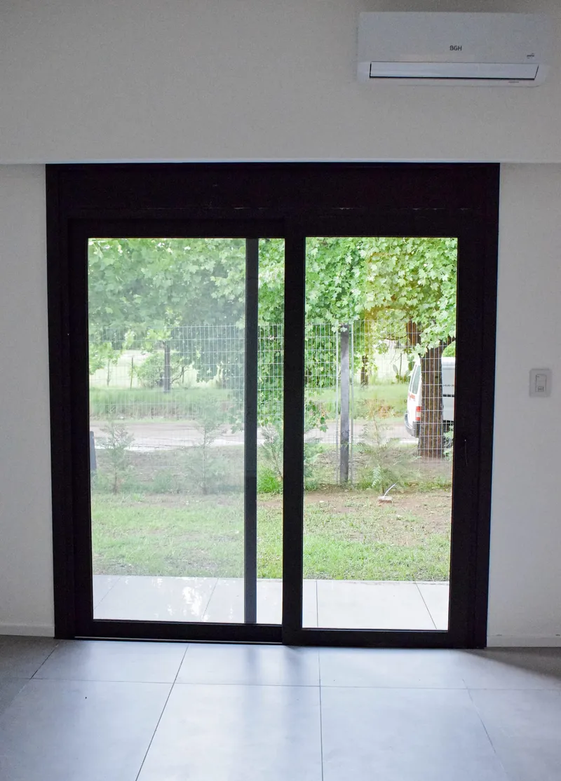 Puerta ventana corrediza de PVC negro con salida al jardín