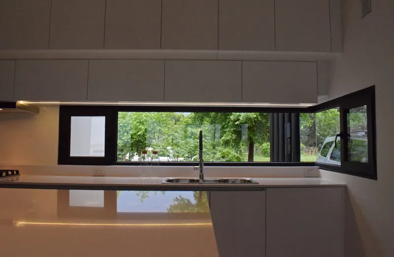 Ventana esquinera de PVC negro sobre la mesada de la cocina