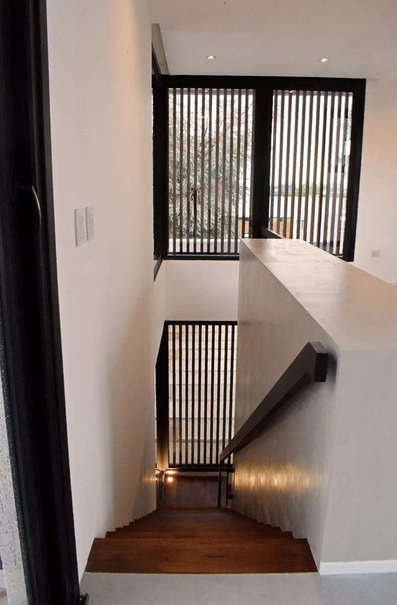 Escalera con paños fijos de PVC negro y celosías de madera